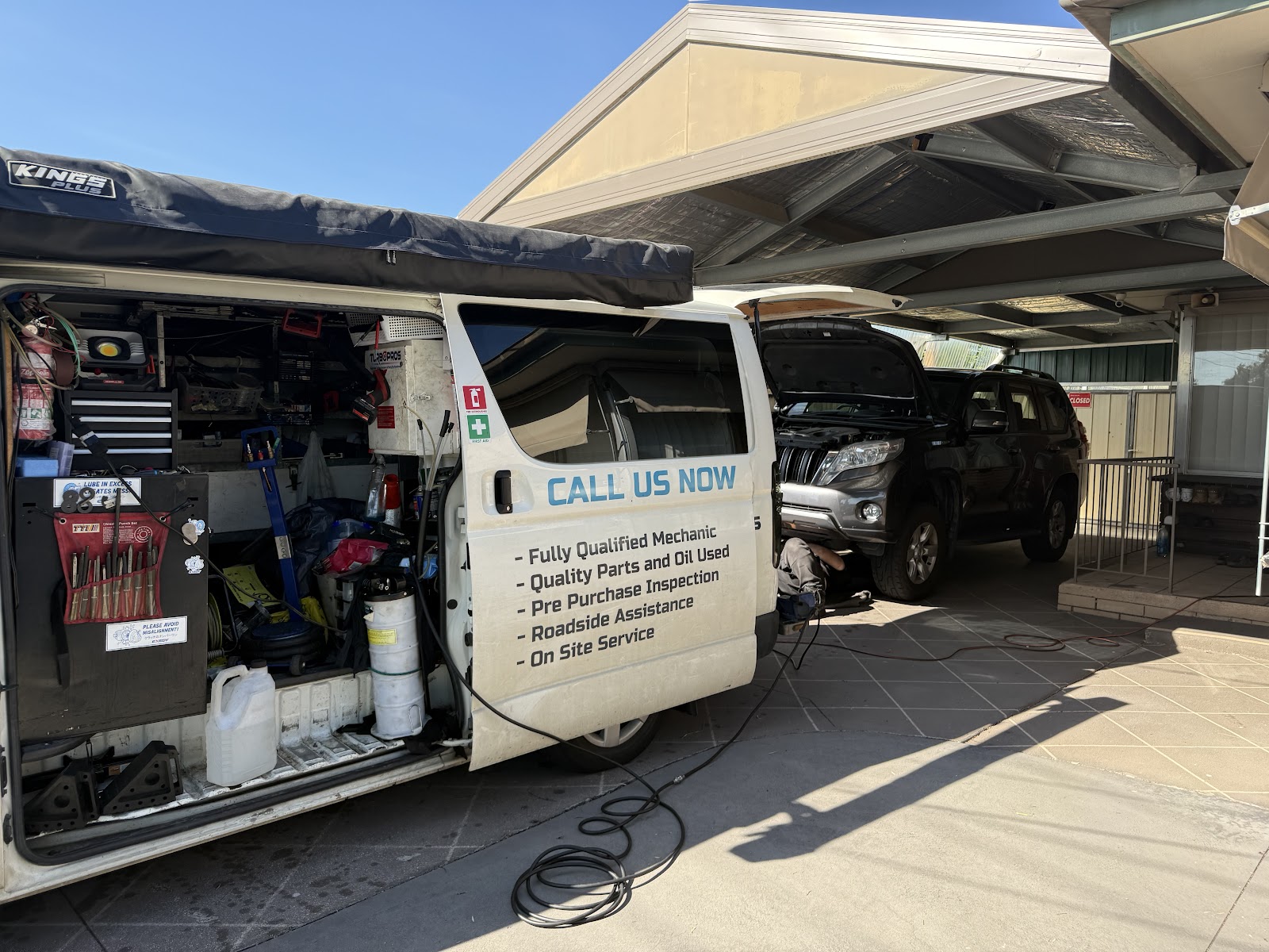 The van's side door open showing tool racks, with CALL US NOW and the service list painted on the door